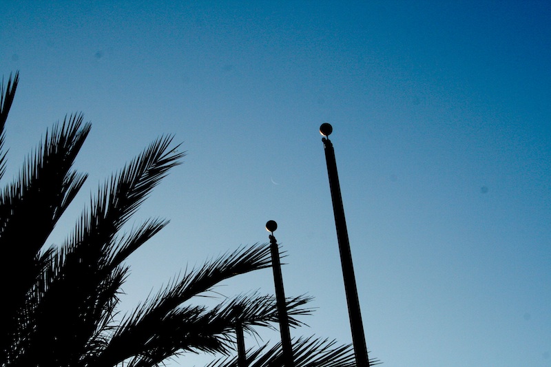 Comparison of the moon in the sky with a flagpole finial, both seen in the same sunshine from the same angle, and both displaying an illuminated crescent shape.