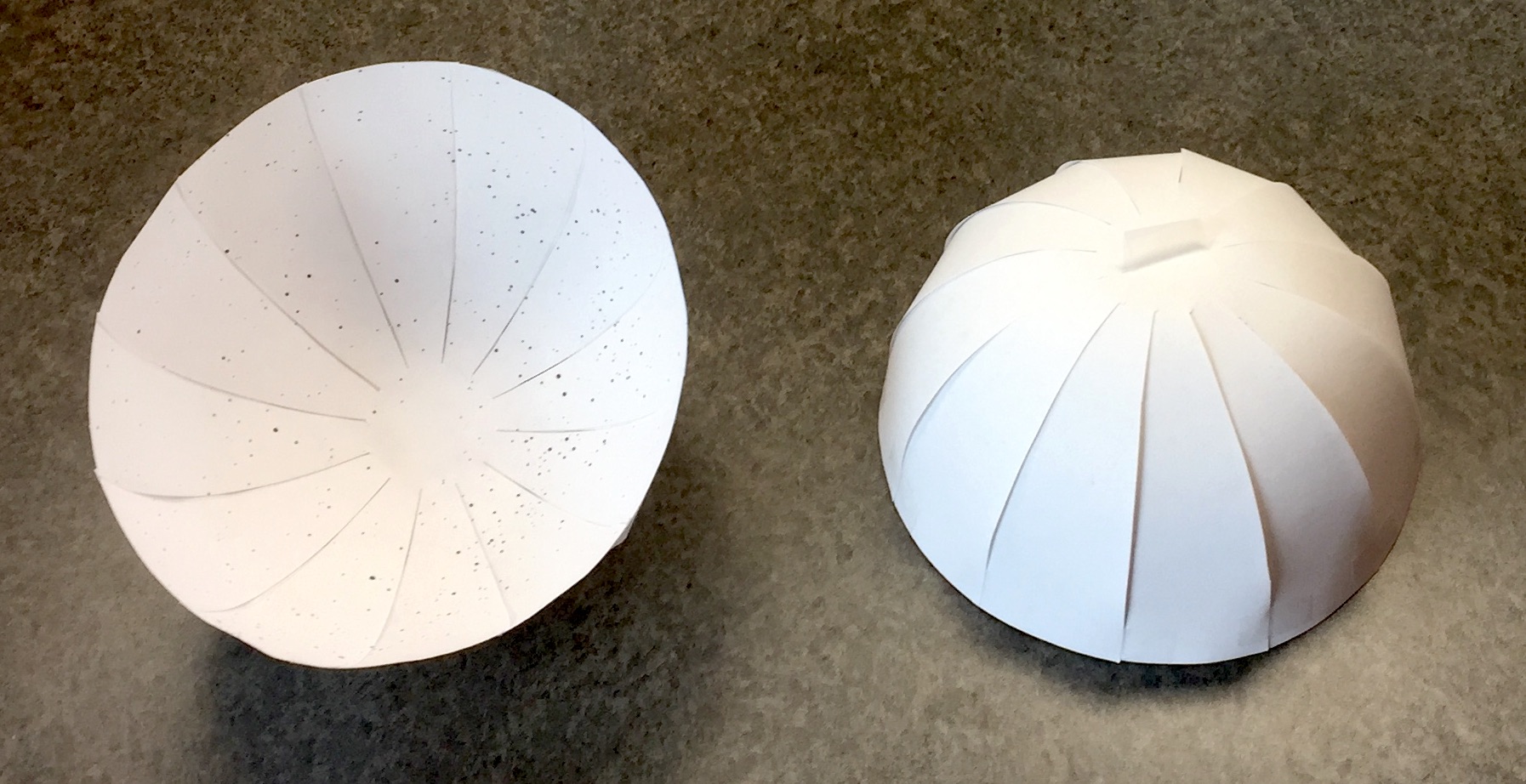 Two hemispheres made of paper, one showing the inside printed with stars, the other showing the outside