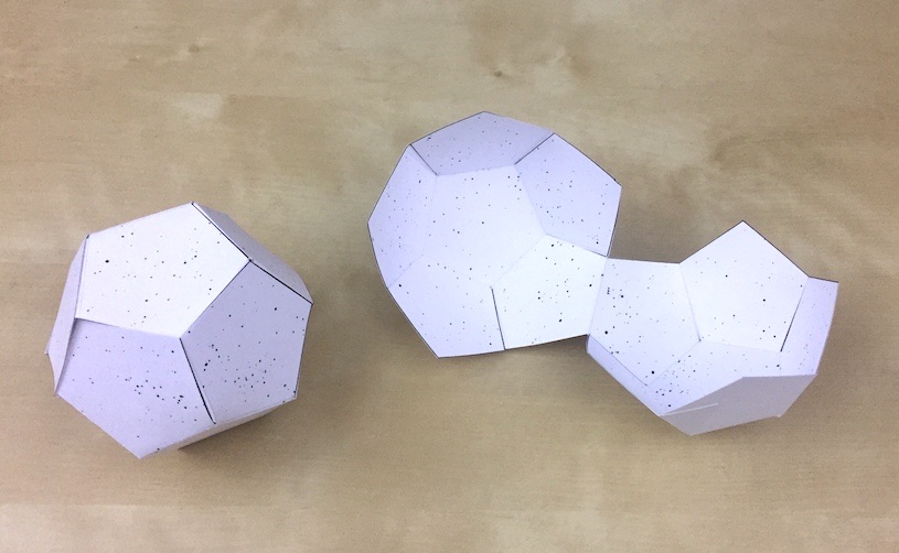 Two paper celestial spheres in the shape of a dodecahedron, one with stars on the outside, and one openable version with stars on the inside