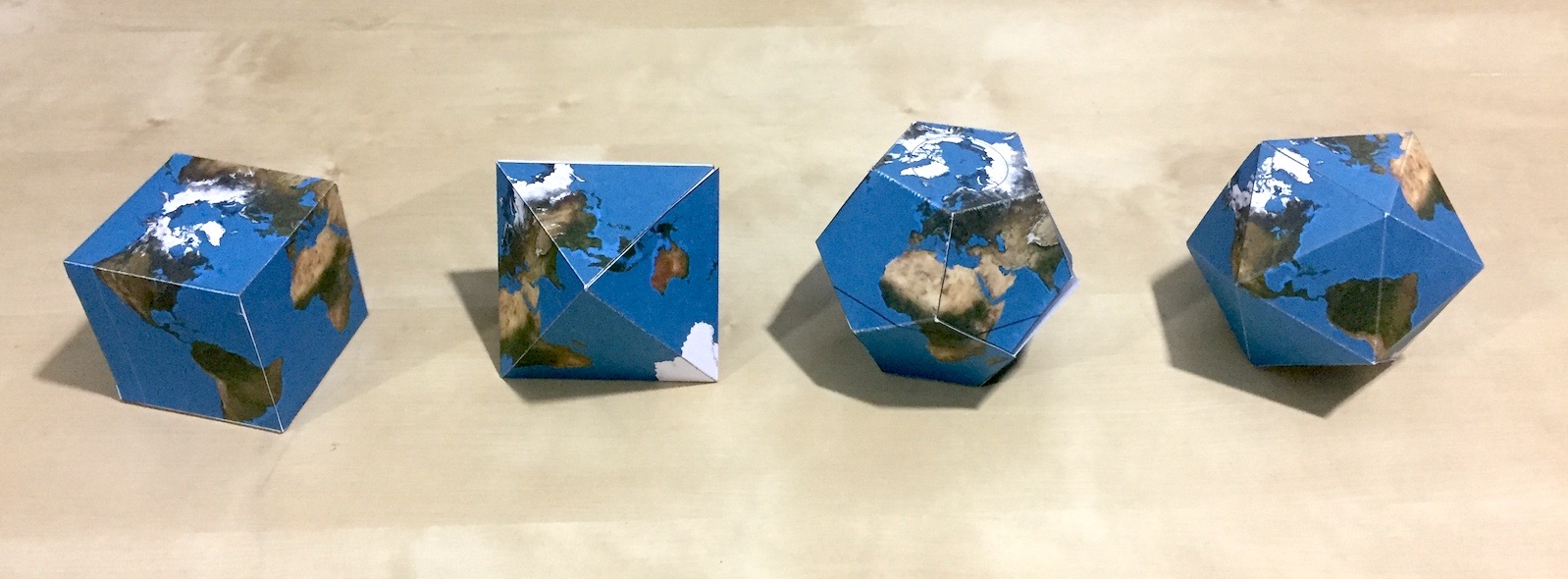Four folded paper globes in the shapes of a cube, an octahedron, a dodecahedron, and an icosahedron